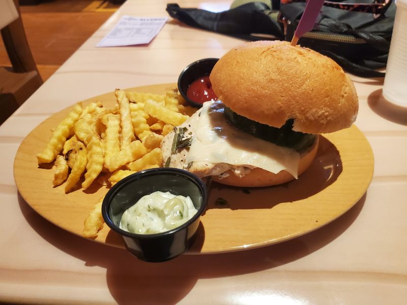 Gluten-free pesto chicken sandwich and fries from Toadstool Cafe at Epic Universe
